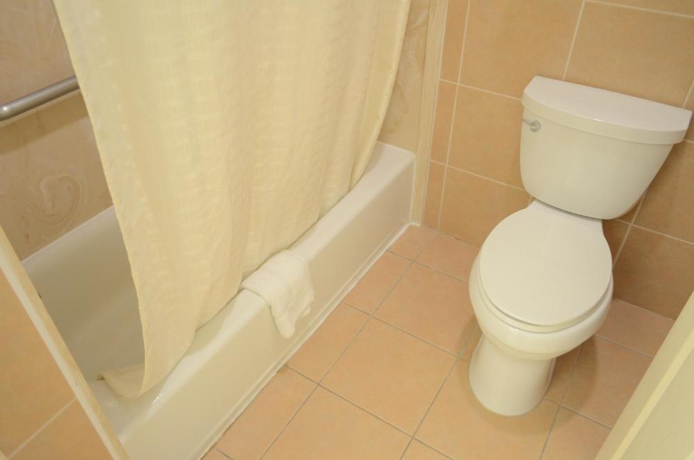 A bathroom with a toilet, bathtub with shower curtain, and tiled floor and walls.