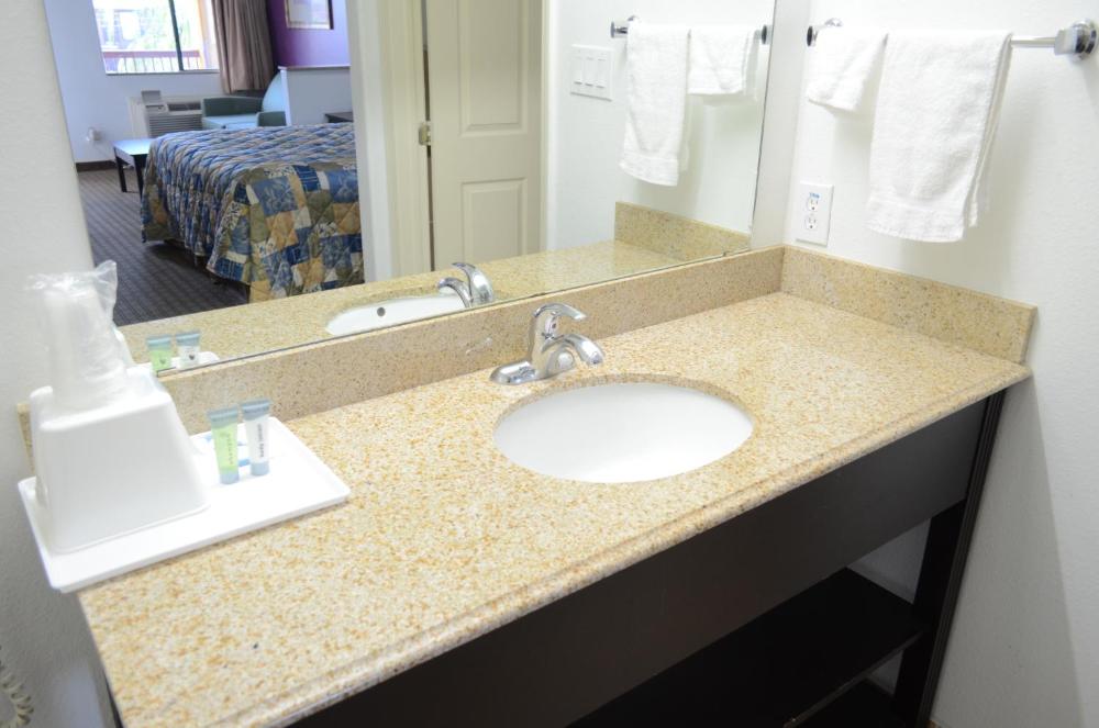 A bathroom sink with a granite countertop and a mirror above it, with towels hanging on the wall.